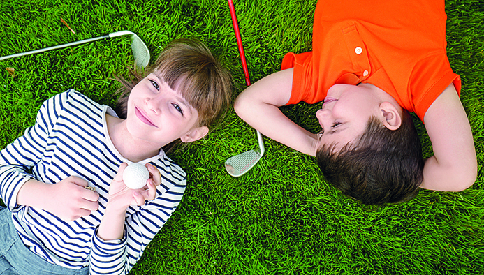 cute children with ball and drivers lying on golf course
