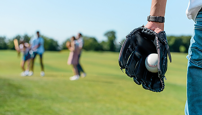 cropped shot of teenager in baseball glove holding ball while playing with friends in park