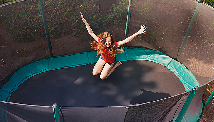 feriencamp - happy teenage girl jumping on trampoline outdoors