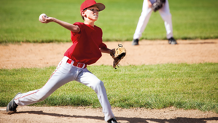 young male baseball pitcher powers through delivery