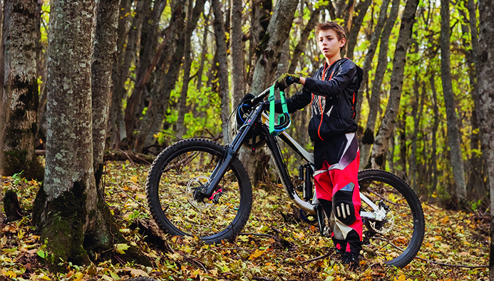 portrait of a young rider in full protection of a full face helmet mask and gloves on a bicycle