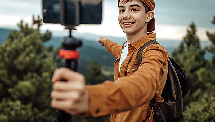 boy hiking and vlogging using mobile phone